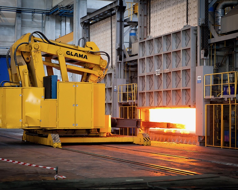 A yellow machine is next to a furnace with flames inside it.