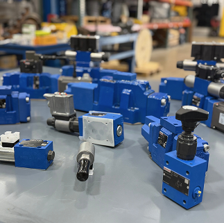 The blurred picture shows various blue mechanical parts scattered around a table with indistinct objects and background details.