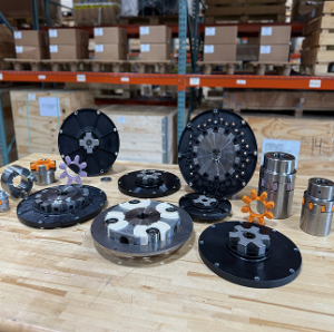 The image is a black and white photo of various mechanical components arranged on a table with shelves in the background.