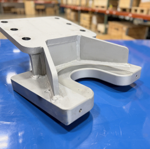 White plastic part with holes and curved edges on blue surface.