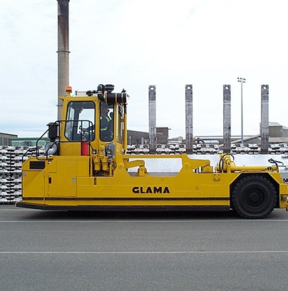 A yellow vehicle with 'GLAMA' written on it is parked near a building and pillars.